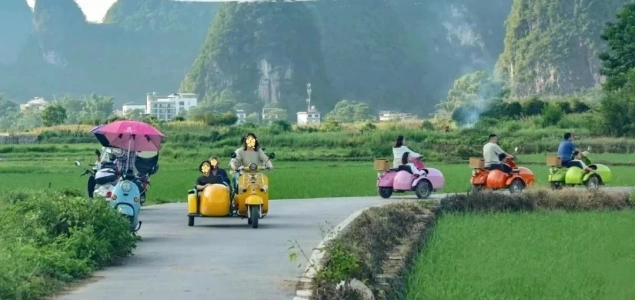 Tourists riding colorful scooters through Yulong River countryside trails