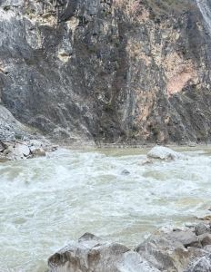 Lower Tiger Leaping Gorge rocky river with cliff background