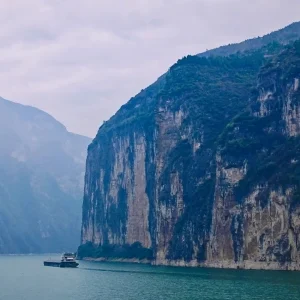 Boat cruising between steep cliffs at Qutang Gorge
